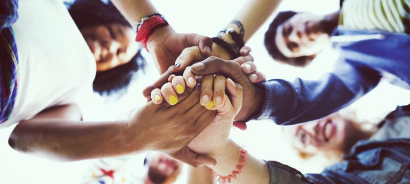 Diverse group of team members putting their hands together